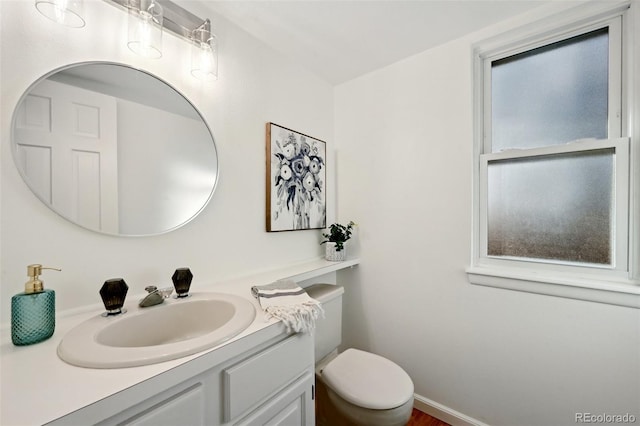 bathroom featuring plenty of natural light, toilet, and vanity