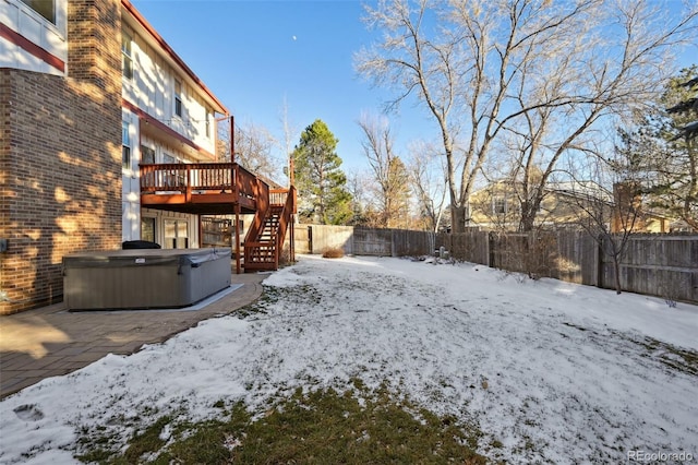 yard covered in snow with a deck and a hot tub