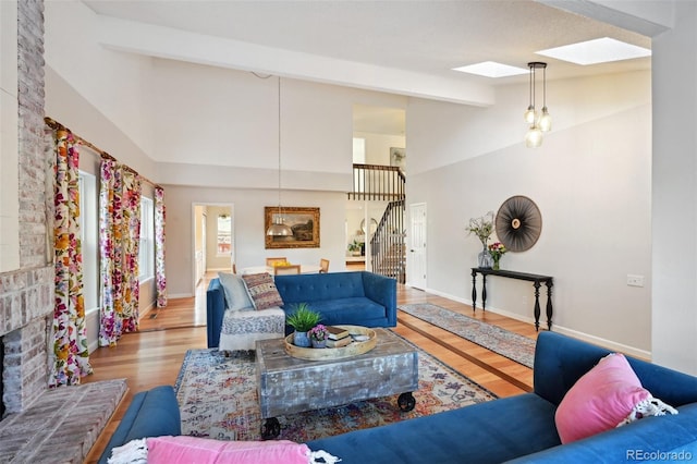 living room featuring a fireplace, light hardwood / wood-style floors, and vaulted ceiling with skylight