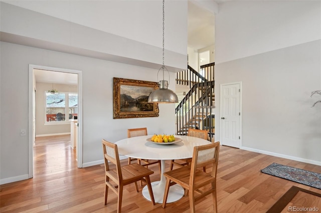 dining area featuring a high ceiling and light hardwood / wood-style flooring