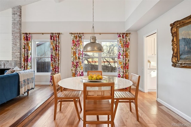 dining space with vaulted ceiling and light hardwood / wood-style flooring