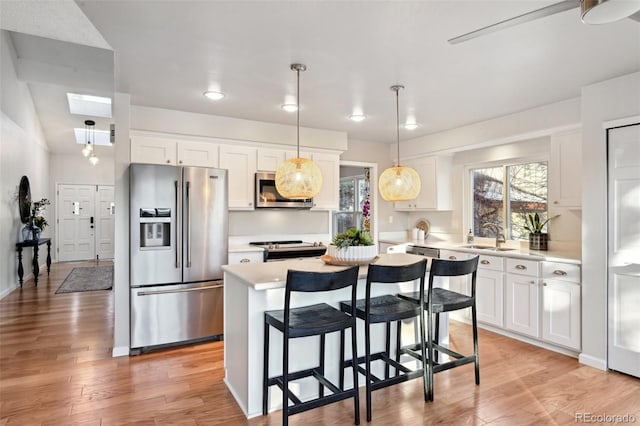 kitchen with appliances with stainless steel finishes, a center island, white cabinetry, and plenty of natural light