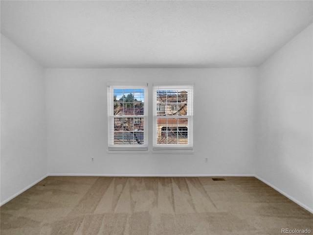 unfurnished room featuring carpet flooring, visible vents, and baseboards