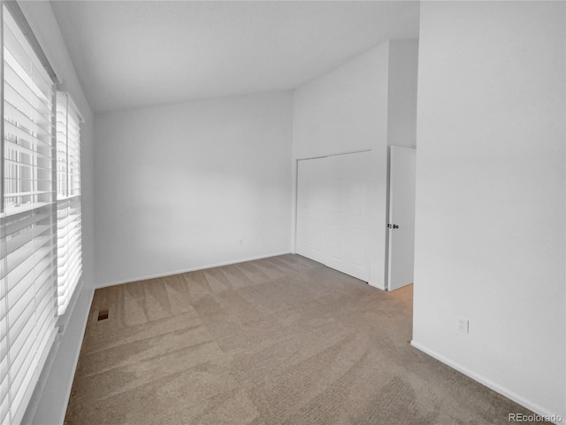 carpeted empty room with lofted ceiling and baseboards