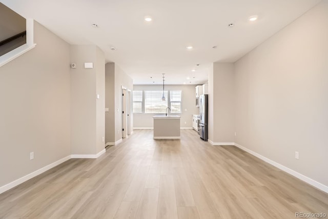 unfurnished living room with sink and light hardwood / wood-style flooring