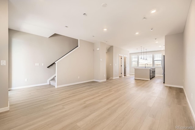 unfurnished living room featuring sink and light wood-type flooring