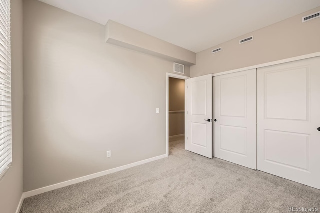 unfurnished bedroom featuring light colored carpet and a closet