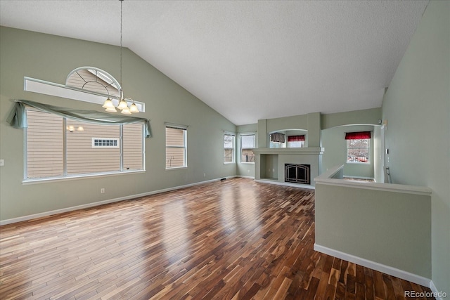 unfurnished living room featuring hardwood / wood-style flooring, a chandelier, high vaulted ceiling, and a textured ceiling