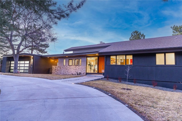 view of front of home with a garage, driveway, and roof with shingles