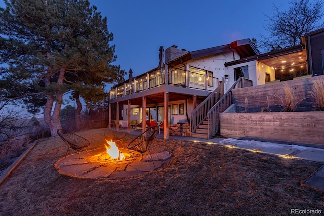 back of house with a fire pit, stairway, a wooden deck, a chimney, and a patio