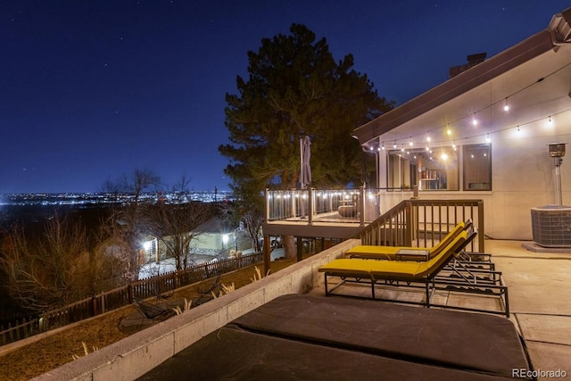 deck at twilight featuring cooling unit and fence