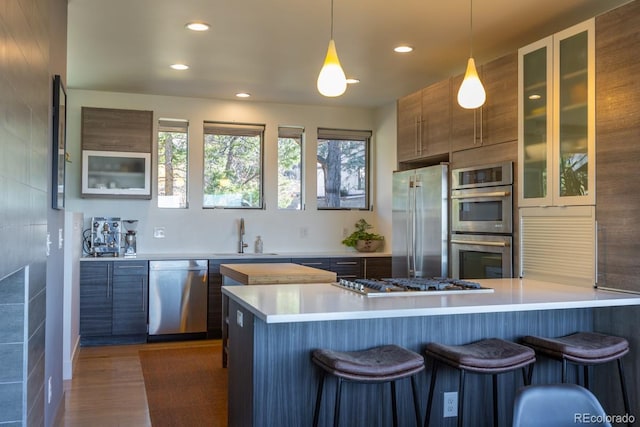 kitchen with a kitchen bar, stainless steel appliances, light countertops, and a sink