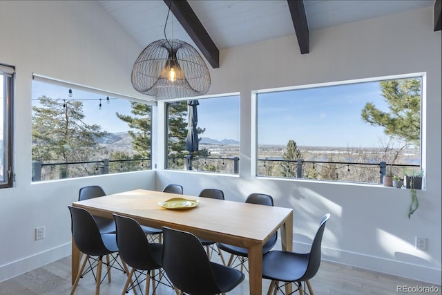 dining area featuring wood finished floors, vaulted ceiling with beams, a healthy amount of sunlight, and baseboards