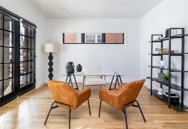 living area with light wood-type flooring, french doors, and a healthy amount of sunlight