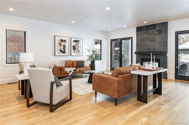 living room with a tile fireplace and light hardwood / wood-style flooring