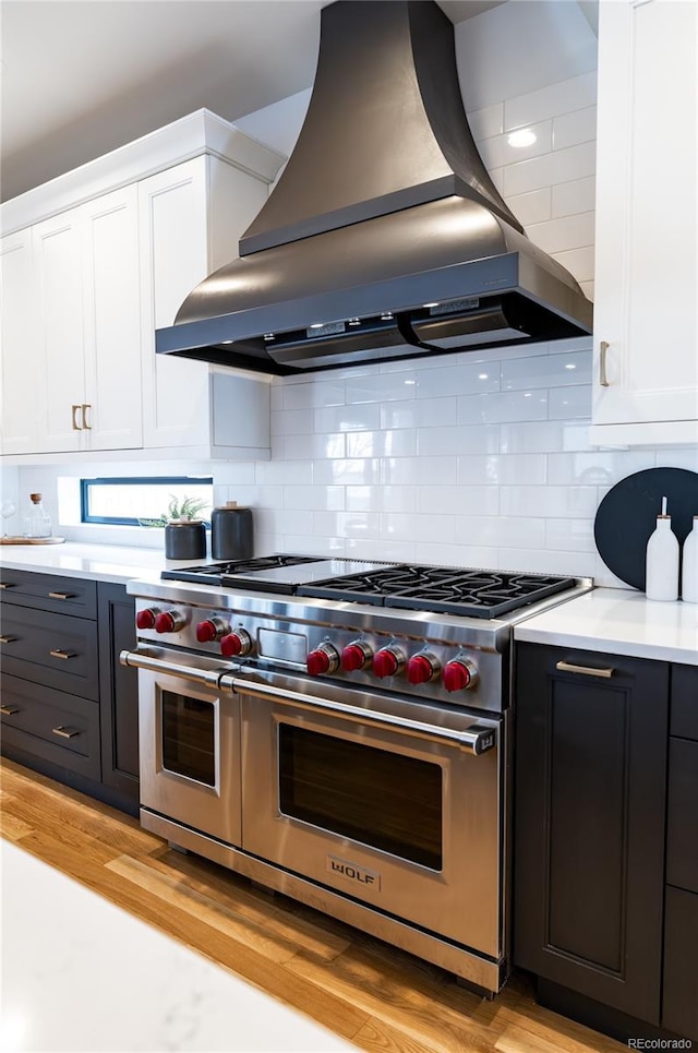 kitchen featuring island range hood, range with two ovens, decorative backsplash, and white cabinetry