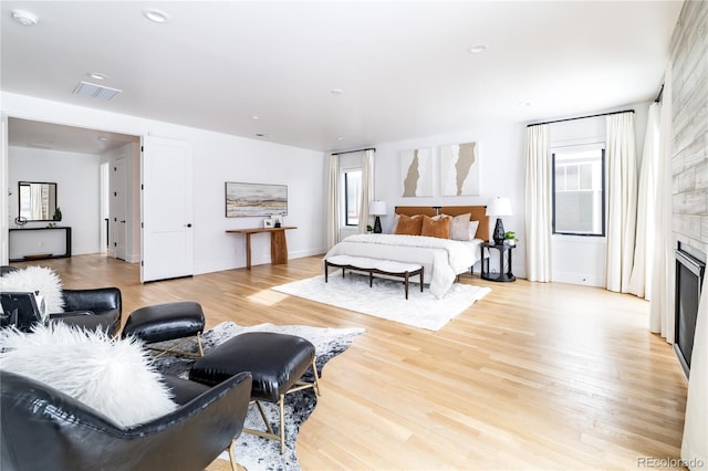 bedroom featuring light wood-type flooring and a large fireplace