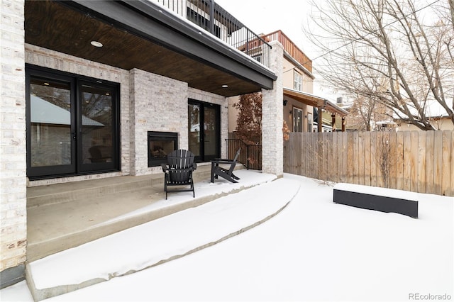 snow covered patio with an outdoor stone fireplace