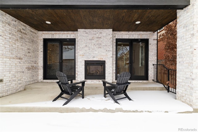 snow covered patio with a large fireplace