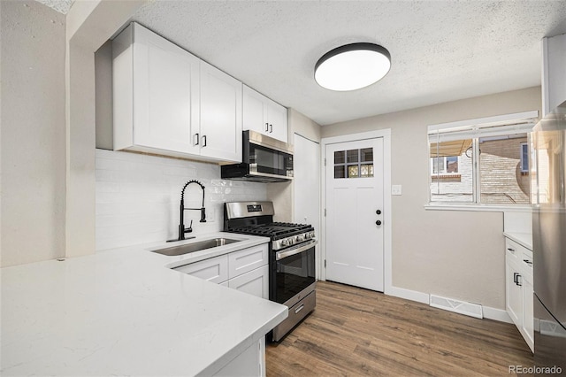 1148 Rosemary St, Denver, CO 80220 - kitchen featuring stainless steel appliances, decorative backsplash, wood finished floors, light countertops, and white cabinetry