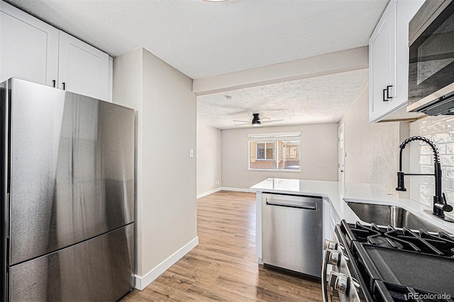 1148 Rosemary St, Denver, CO 80220 - kitchen featuring stainless steel appliances, a textured ceiling, white cabinetry, light wood-style flooring, and a ceiling fan