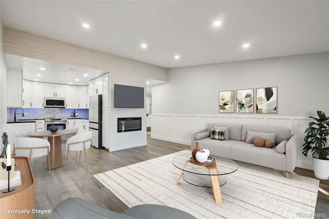 living room with sink, a large fireplace, and wood-type flooring