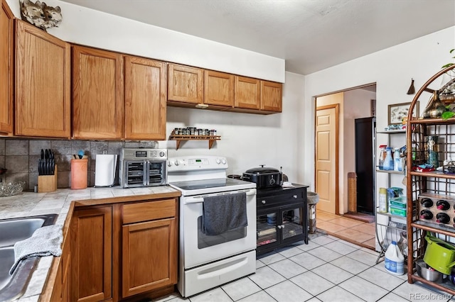 4940-42 W 9th Ave W, Denver, CO 80204 - kitchen with electric stove, tile counters, open shelves, brown cabinetry, and light tile patterned floors