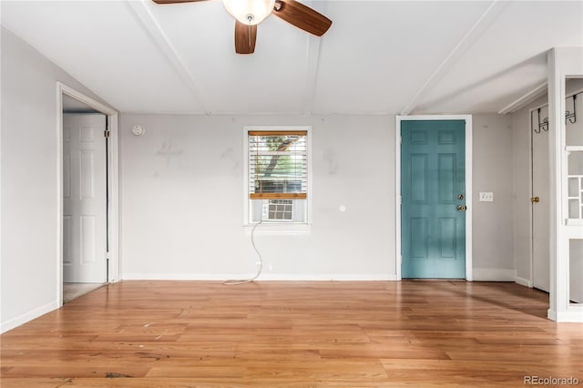 empty room featuring lofted ceiling, light wood-style flooring, baseboards, and a ceiling fan