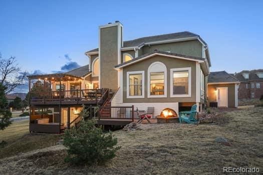 back of house with a chimney, a fire pit, and a deck