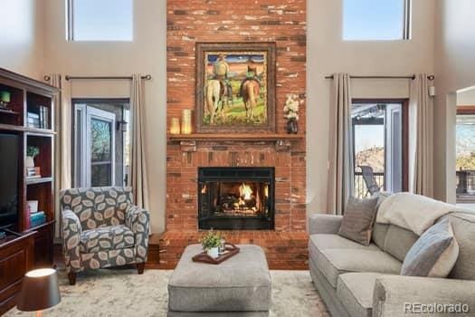 living room with a brick fireplace, plenty of natural light, and a high ceiling