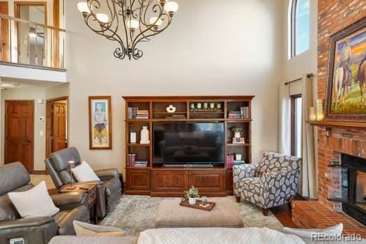 living area with a notable chandelier, a fireplace, and a towering ceiling