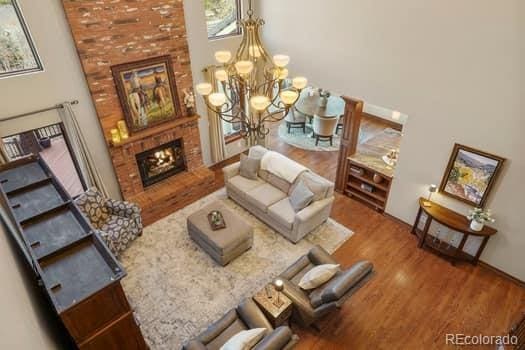 living room with a fireplace, wood finished floors, a towering ceiling, and an inviting chandelier