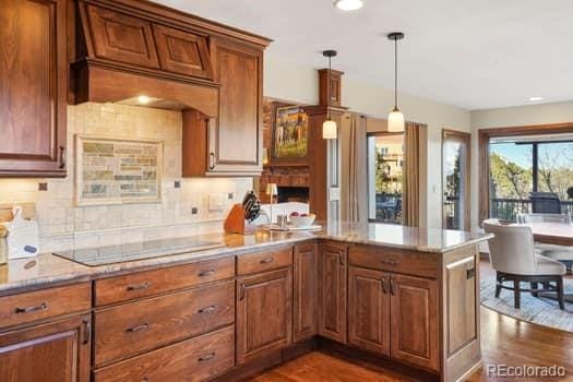 kitchen with a peninsula, black electric cooktop, and brown cabinets