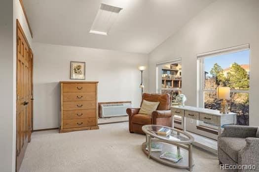 sitting room with carpet floors, lofted ceiling, and a wall mounted air conditioner