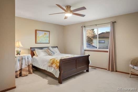 carpeted bedroom with ceiling fan and baseboards