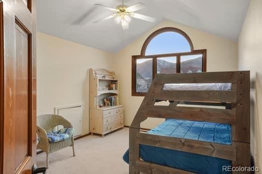 carpeted bedroom featuring a ceiling fan and vaulted ceiling