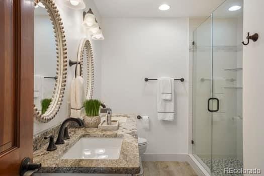 bathroom featuring toilet, recessed lighting, vanity, baseboards, and a shower stall