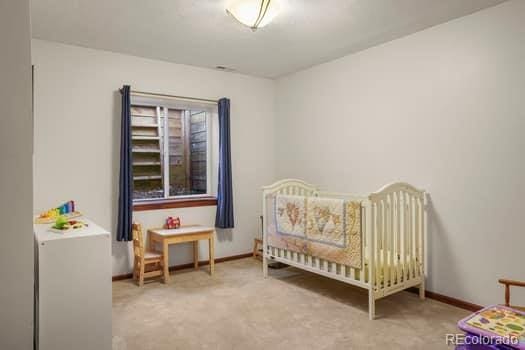 bedroom featuring a nursery area, carpet floors, and baseboards