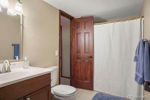 bathroom with toilet, a shower with shower curtain, vanity, and tile patterned floors