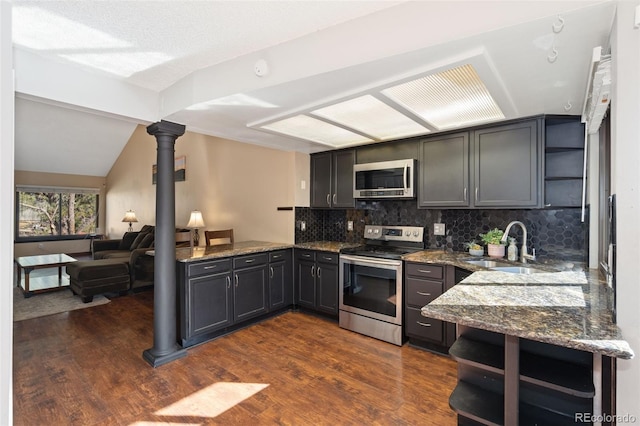 kitchen with dark wood finished floors, open shelves, appliances with stainless steel finishes, and dark stone counters