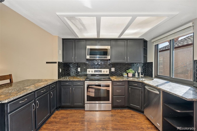 kitchen featuring dark stone countertops, open shelves, a sink, stainless steel appliances, and dark wood-type flooring