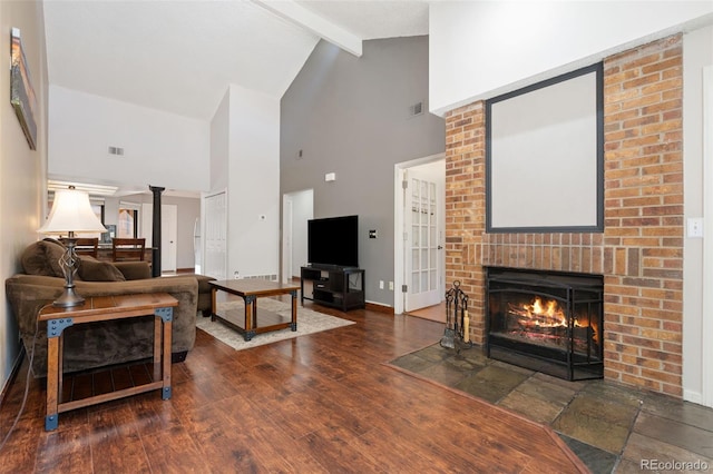 living area featuring visible vents, baseboards, beam ceiling, a fireplace, and wood finished floors