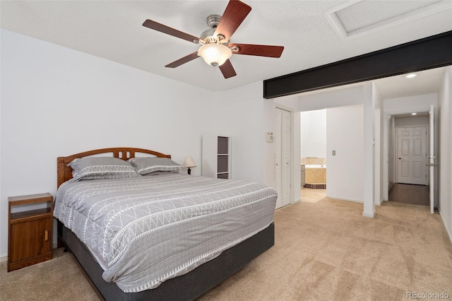 bedroom featuring light carpet, attic access, ensuite bath, and a ceiling fan