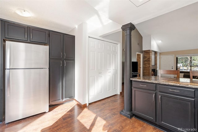 kitchen featuring light stone counters, lofted ceiling, freestanding refrigerator, and dark wood-type flooring