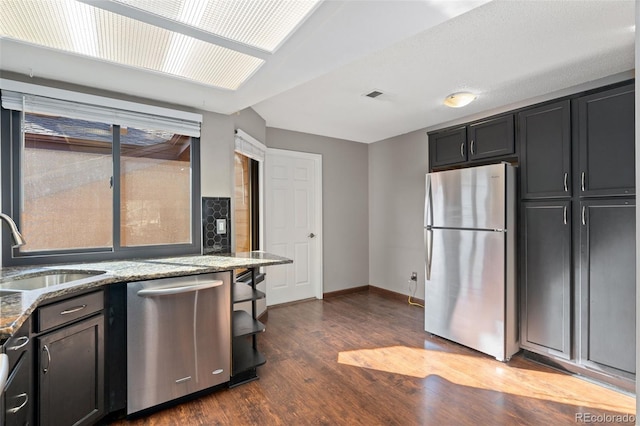 kitchen featuring visible vents, light stone countertops, dark wood finished floors, appliances with stainless steel finishes, and a sink