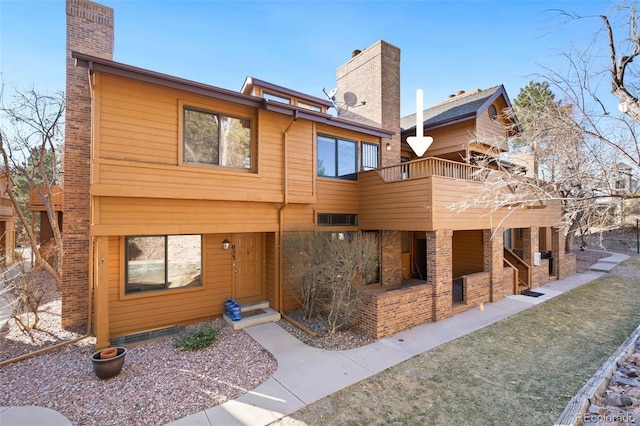 rear view of property featuring a chimney and a patio