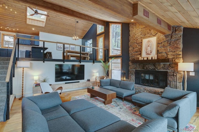 living room featuring wood ceiling, a stone fireplace, stairs, wood finished floors, and a chandelier