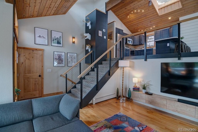 living area with a baseboard heating unit, stairs, wood finished floors, a skylight, and wooden ceiling