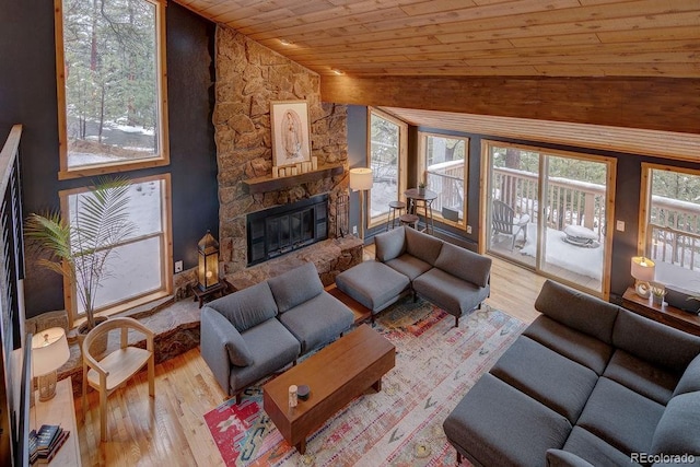 living room featuring vaulted ceiling, wood ceiling, a stone fireplace, and wood finished floors