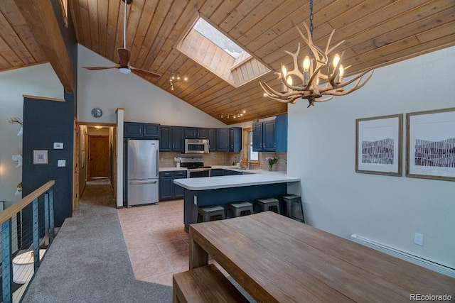 kitchen featuring stainless steel appliances, a skylight, a chandelier, light countertops, and blue cabinetry